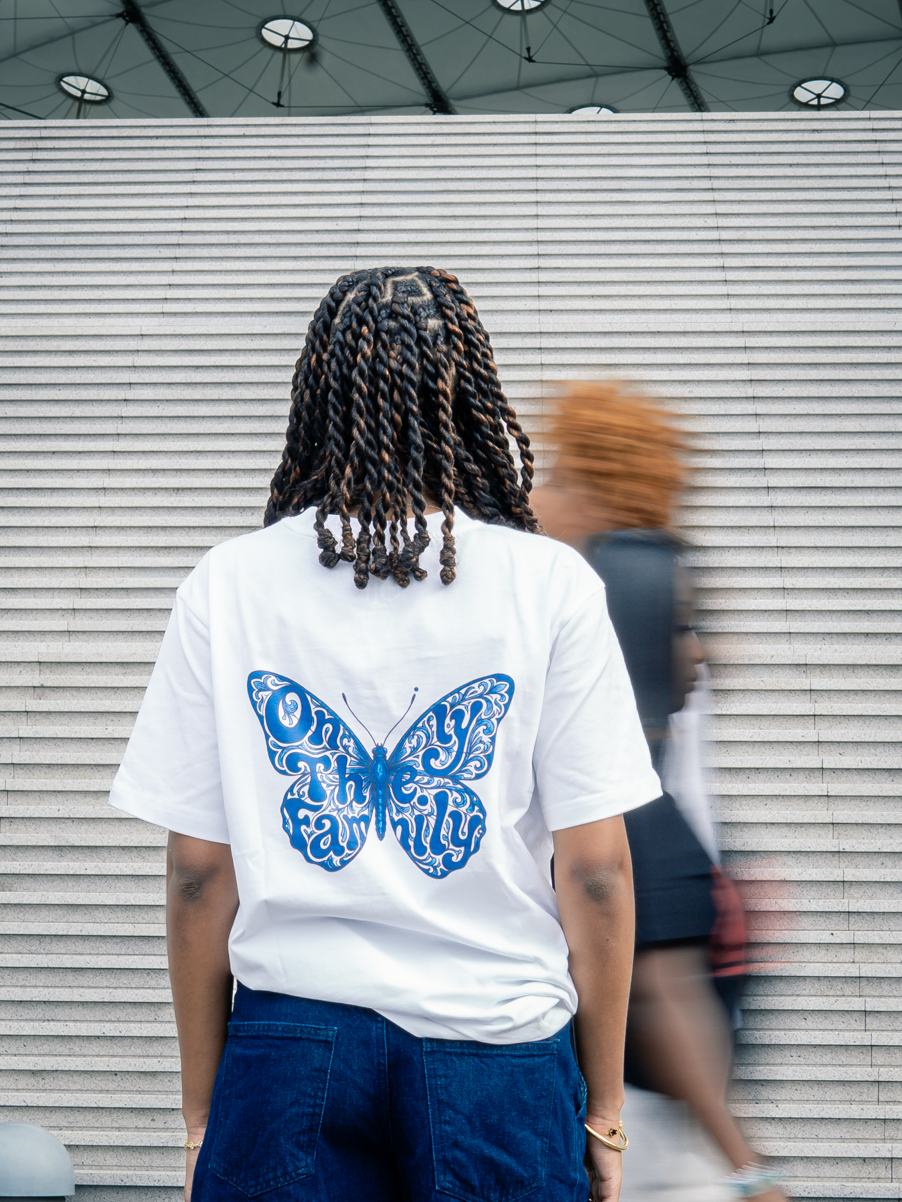 Dos d'un t-shirt blanc Only The Family avec un grand motif de papillon bleu.