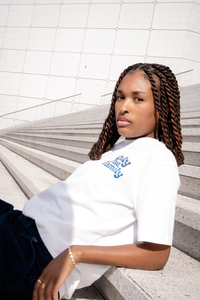 Modèle portant un t-shirt blanc Only The Family avec un grand motif de papillon bleu
